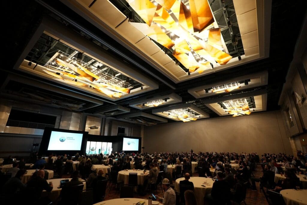 A banquet hall filled with people for a corporate presentation.