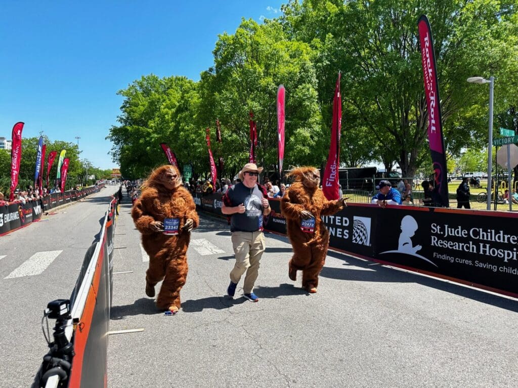 Two people dressed up in costumes crossing the finish line of a marathon.