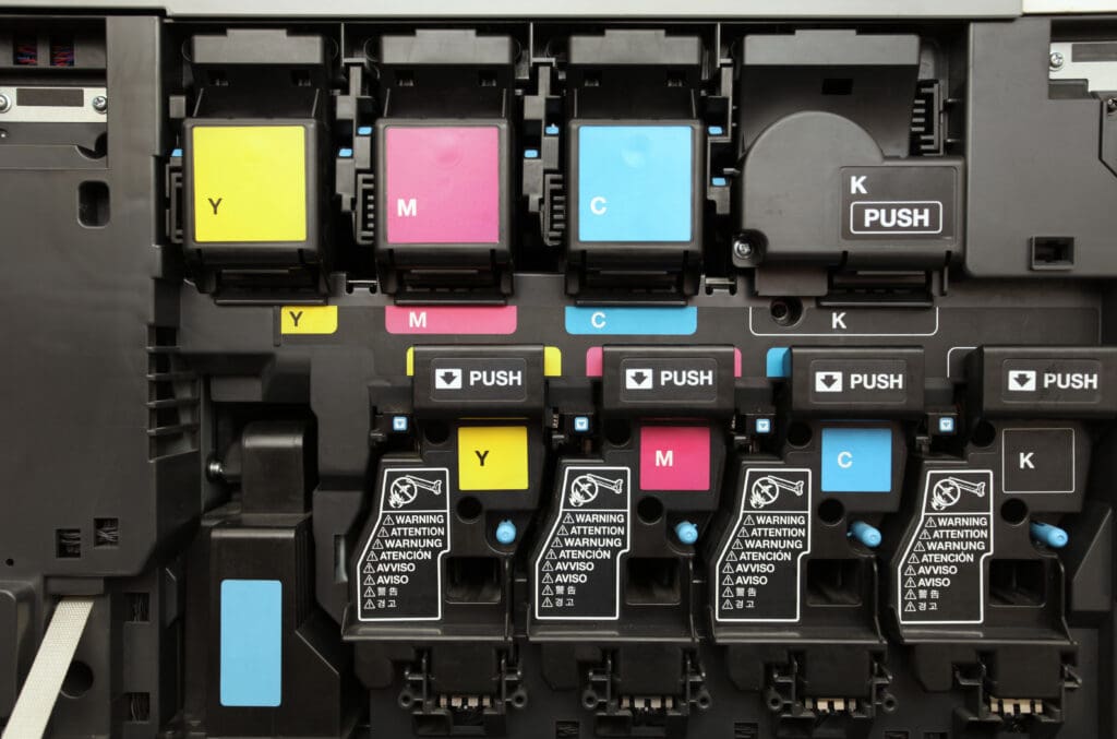 An image showing four CMYK ink cartridges arranged side by side. The cartridges are labeled with their respective colors: cyan, magenta, yellow, and black. Each cartridge is designed to fit into a printer, representing the essential colors used in the printing process.