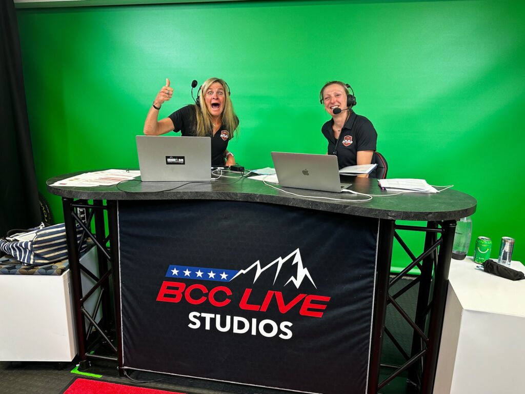 Broadcast hosts sitting at the broadcast desk.